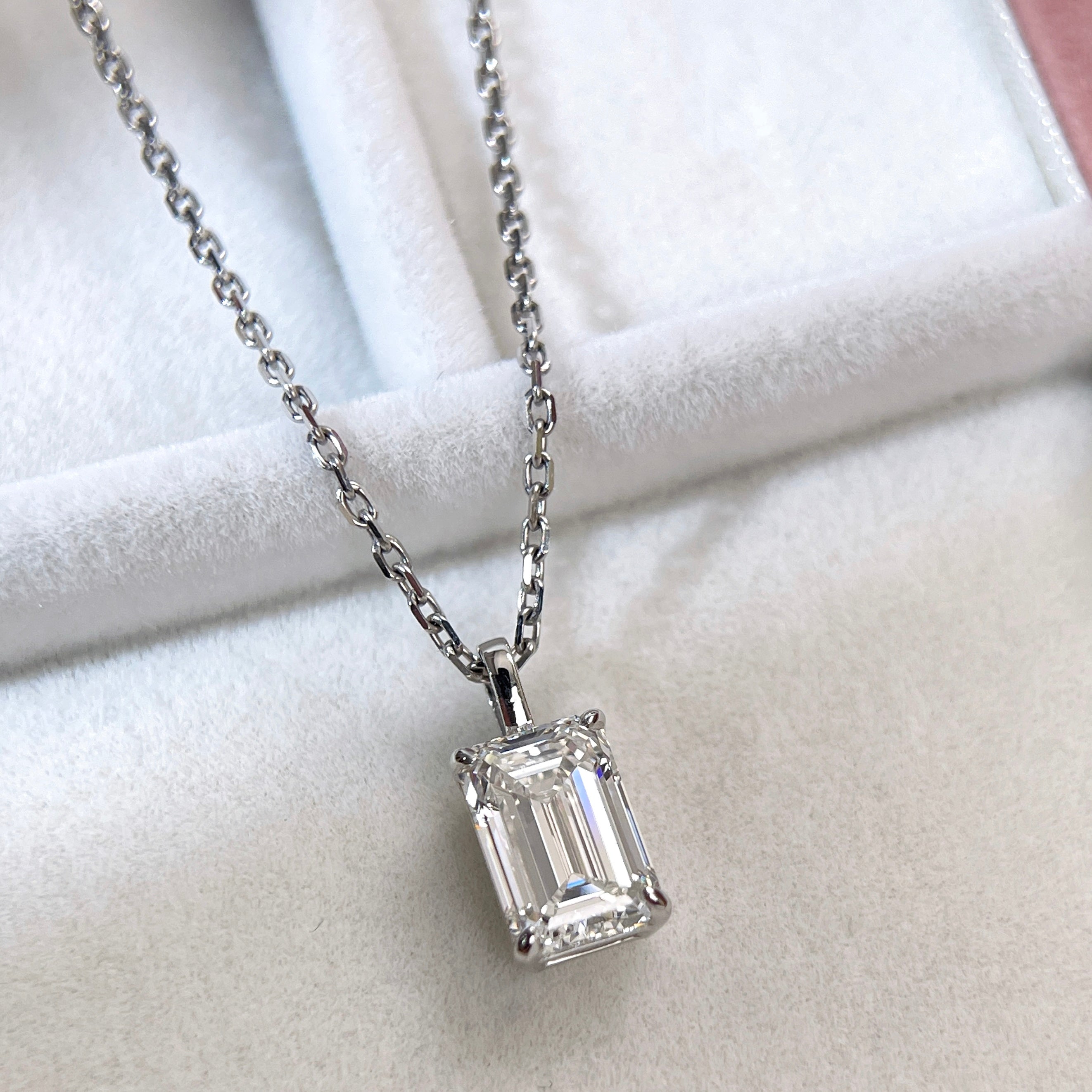 Close-up display of the emerald-cut diamond and four-prong setting on an 18K white gold pendant