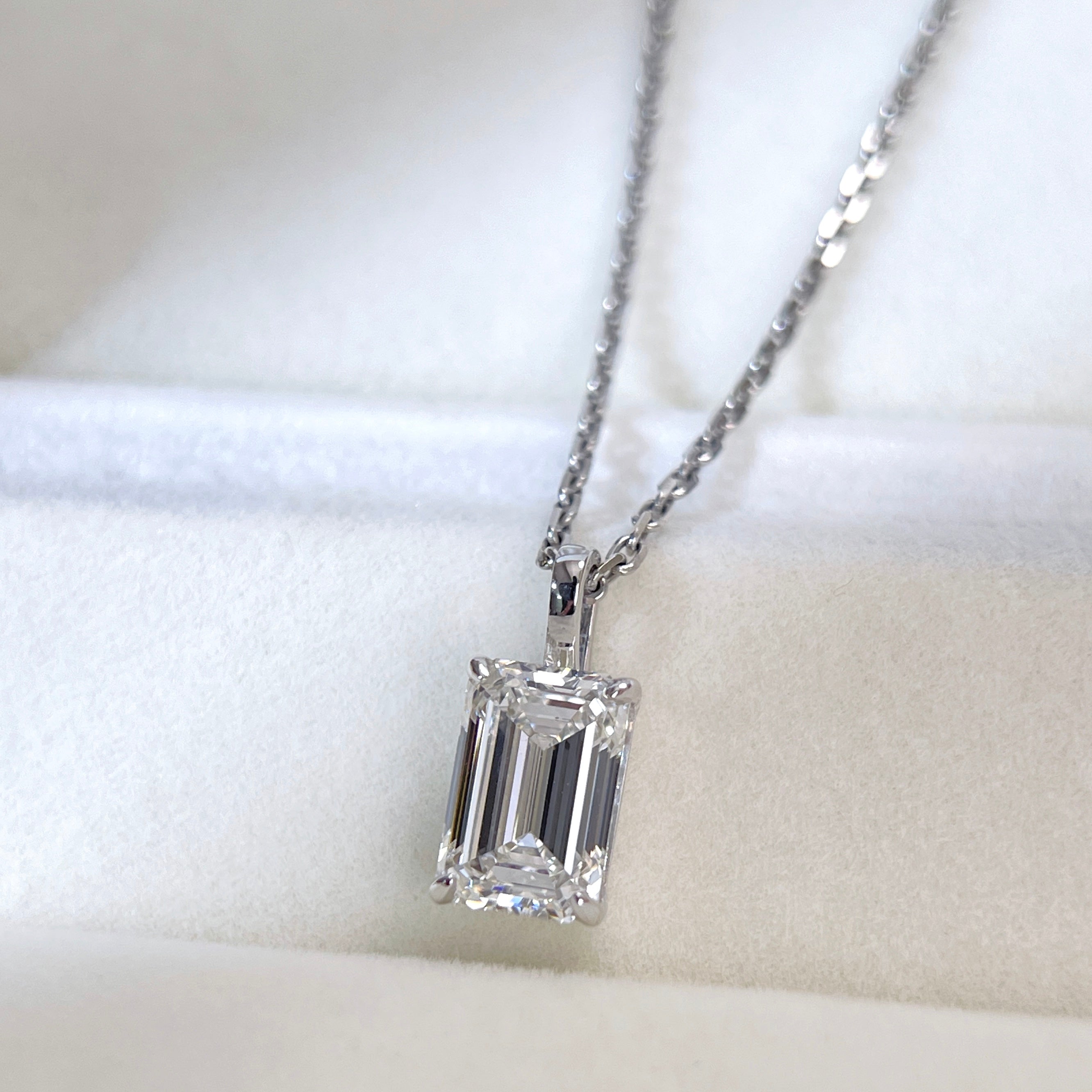 Detail view of an emerald-cut lab grown diamond 18K white gold pendant and its bail