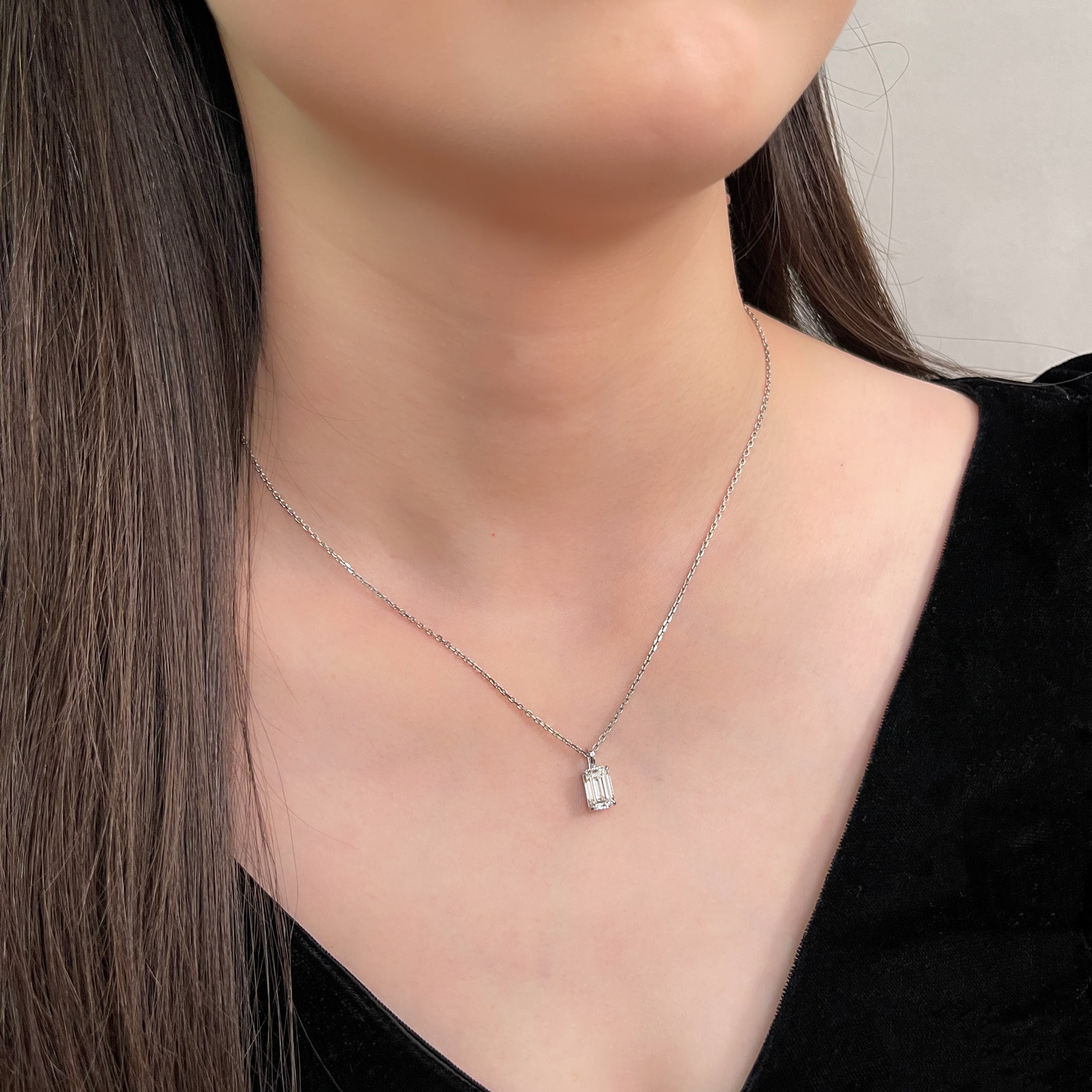 Close-up of a model wearing a 2 ct emerald-cut lab grown diamond pendant on a separate chain