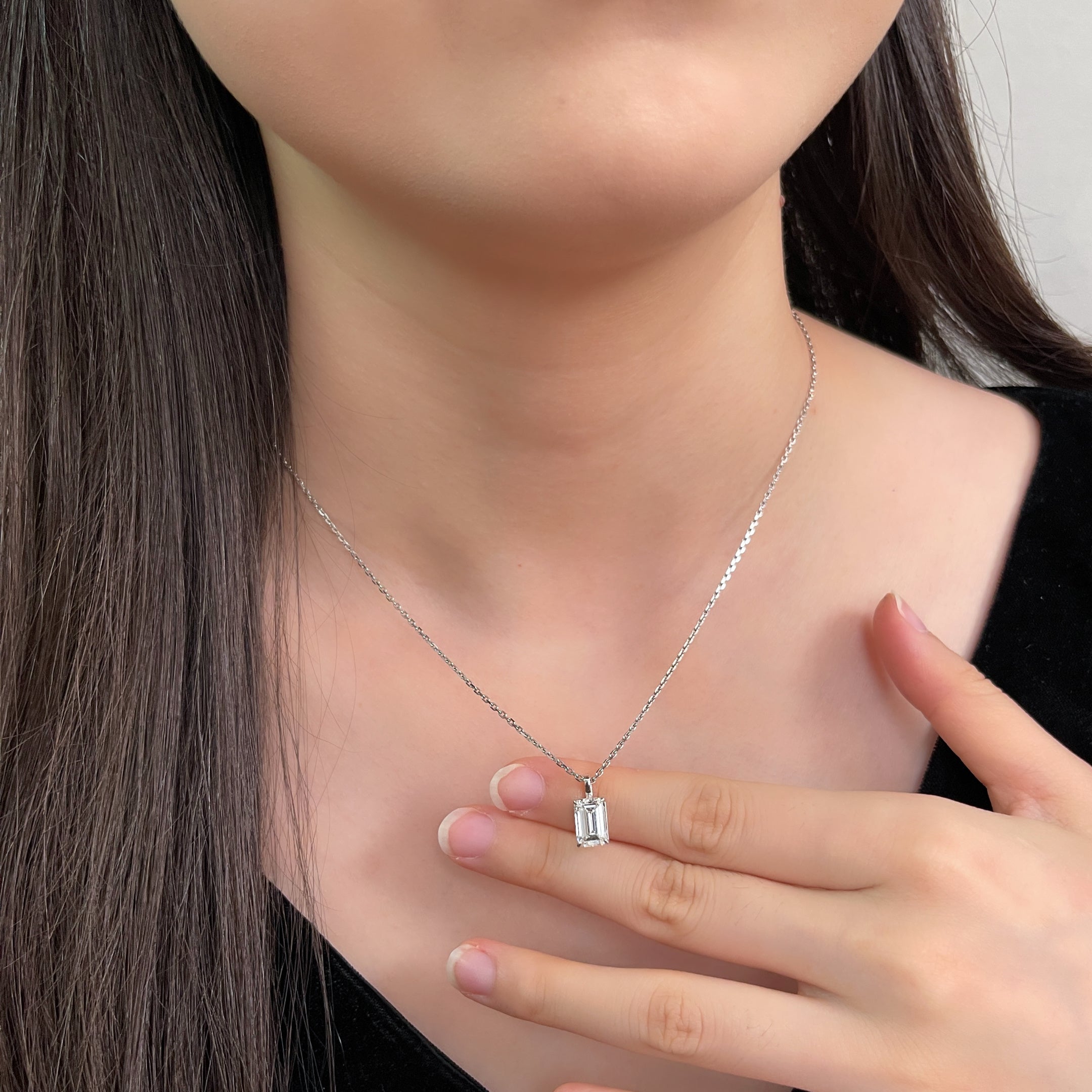 Model holding the detachable emerald-cut lab grown diamond pendant while wearing its chain
