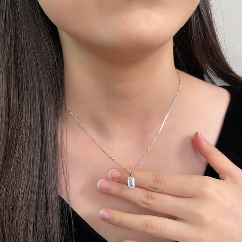 Model holding the detachable emerald-cut lab grown diamond pendant while wearing its chain