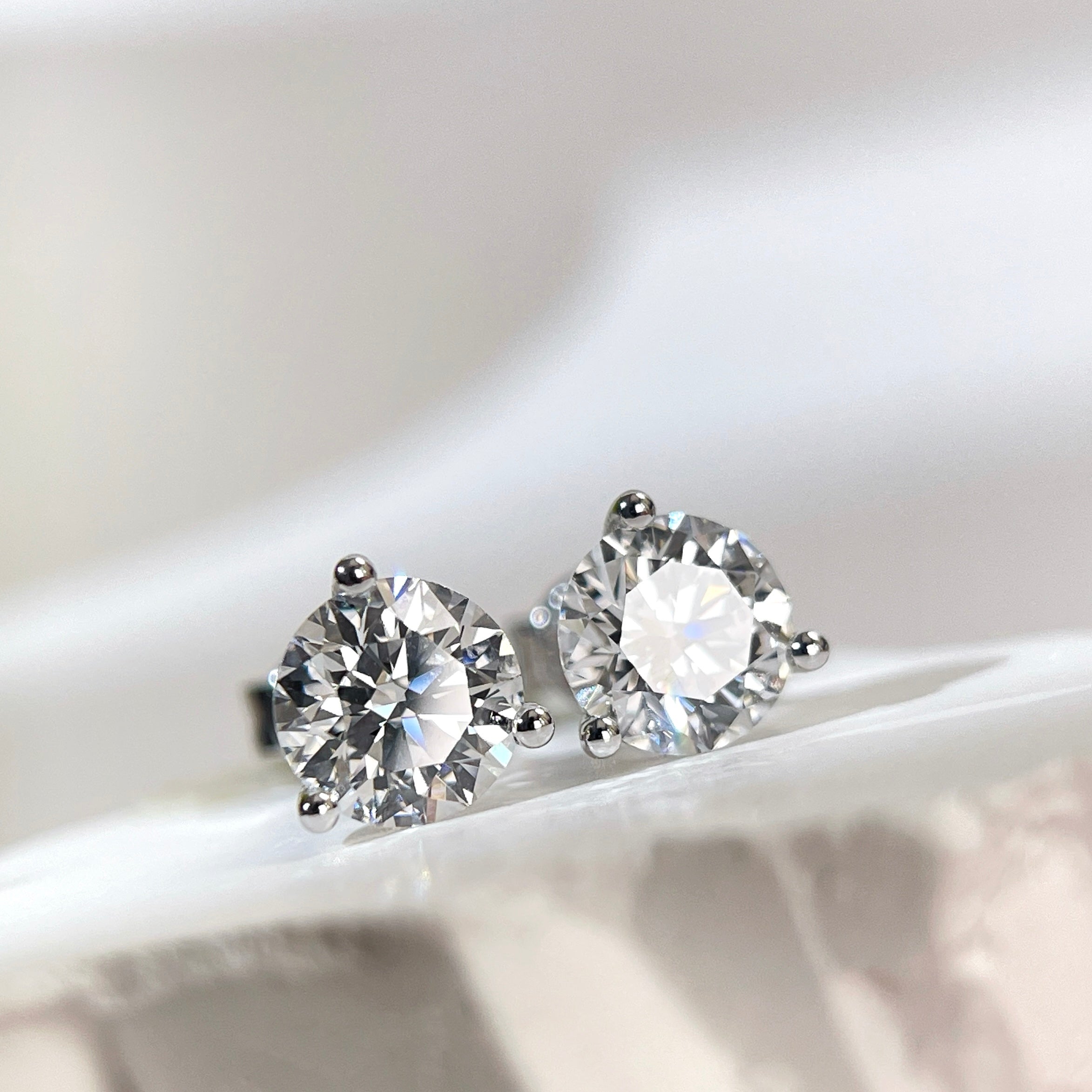 Angled front view of D VVS2 round lab grown diamond Martini stud earrings