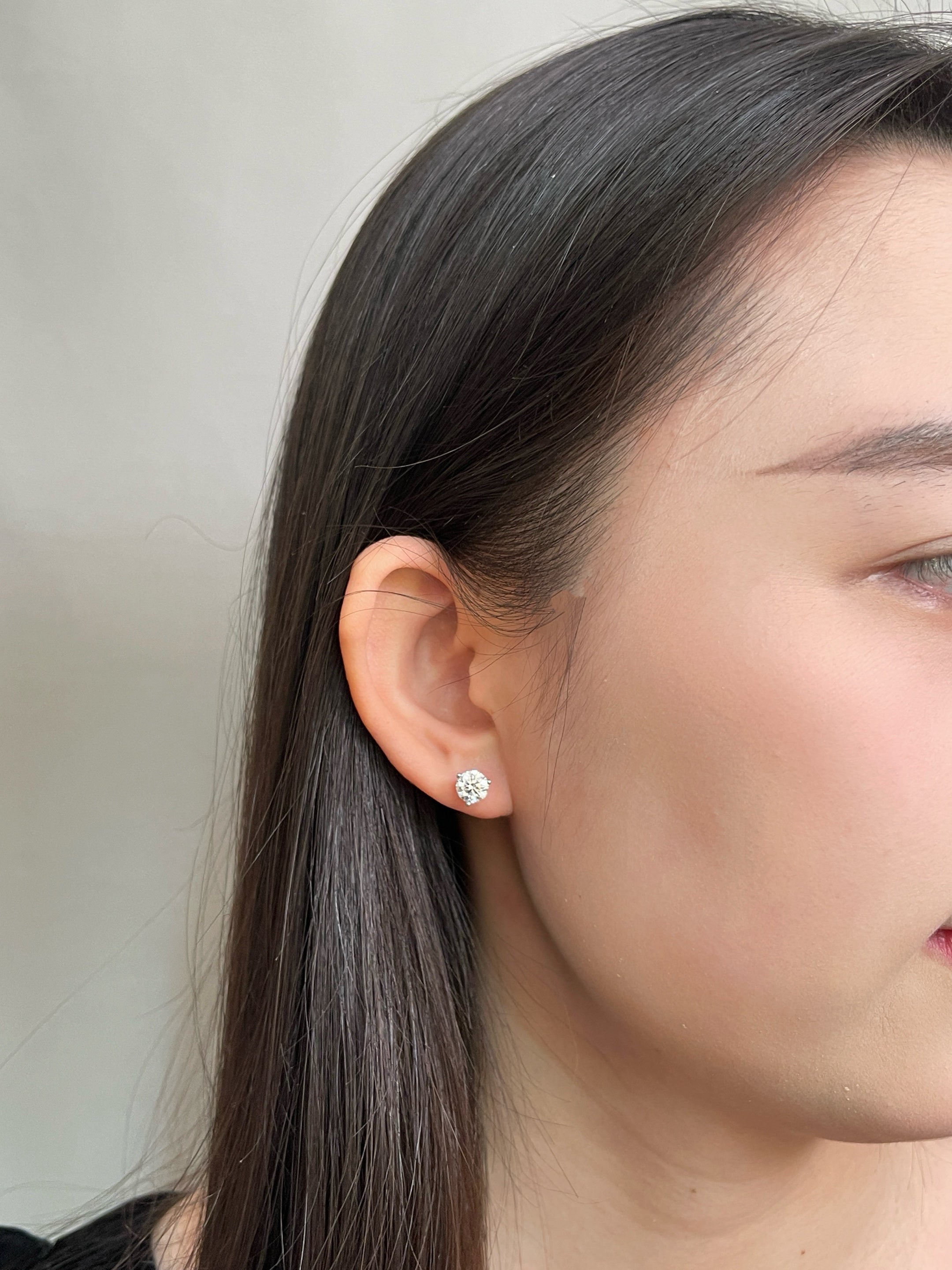 Model wearing a 2 CTW pair of round lab grown diamond three-prong Martini stud earrings
