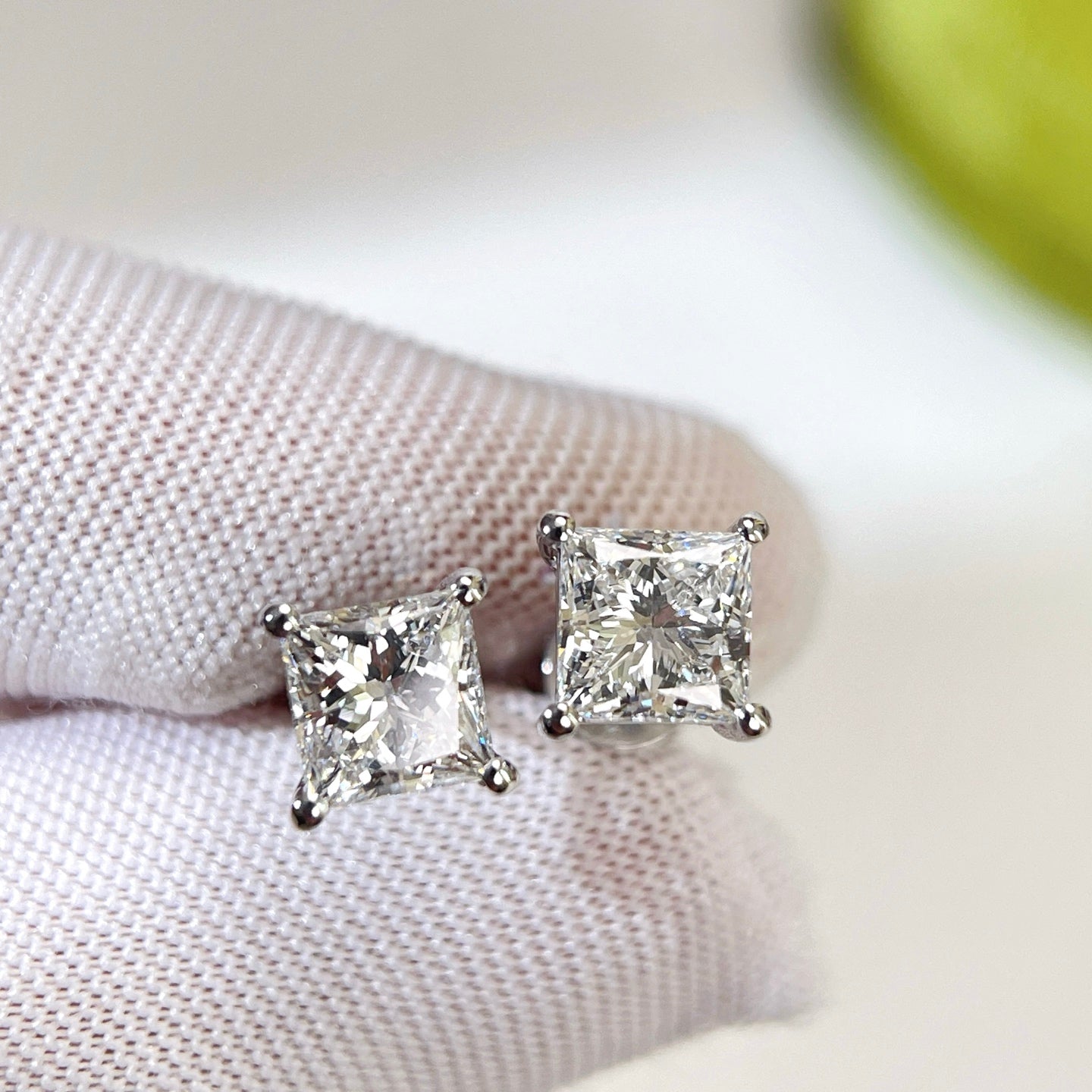 Gloved-hand close-up of princess-cut lab-grown diamonds in four-prong settings