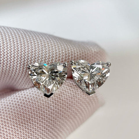Gloved-hand close-up of heart-shaped lab-grown diamonds in three-prong settings