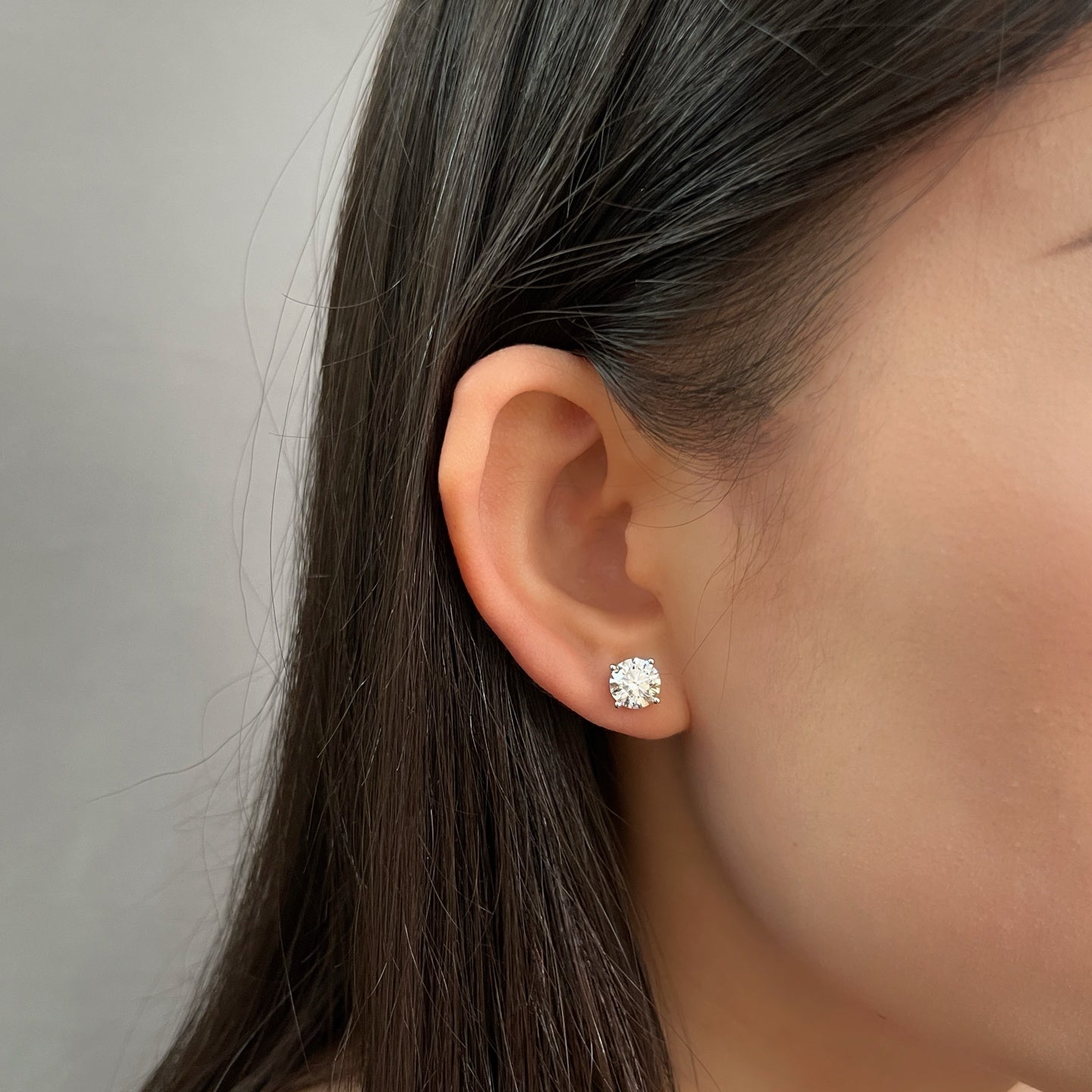 Model wearing 3 CTW round lab grown diamond four-prong stud earrings