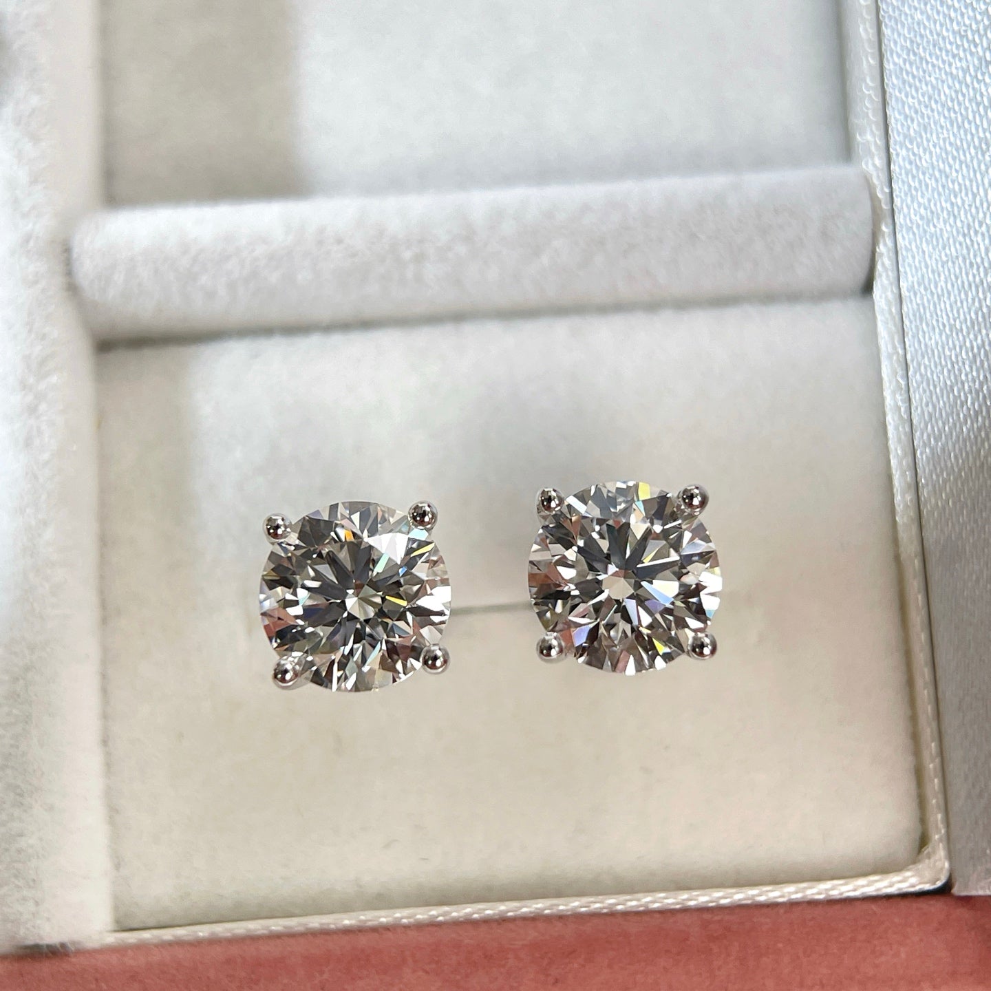 Top view of 3 CTW round lab grown diamond stud earrings in a jewelry box