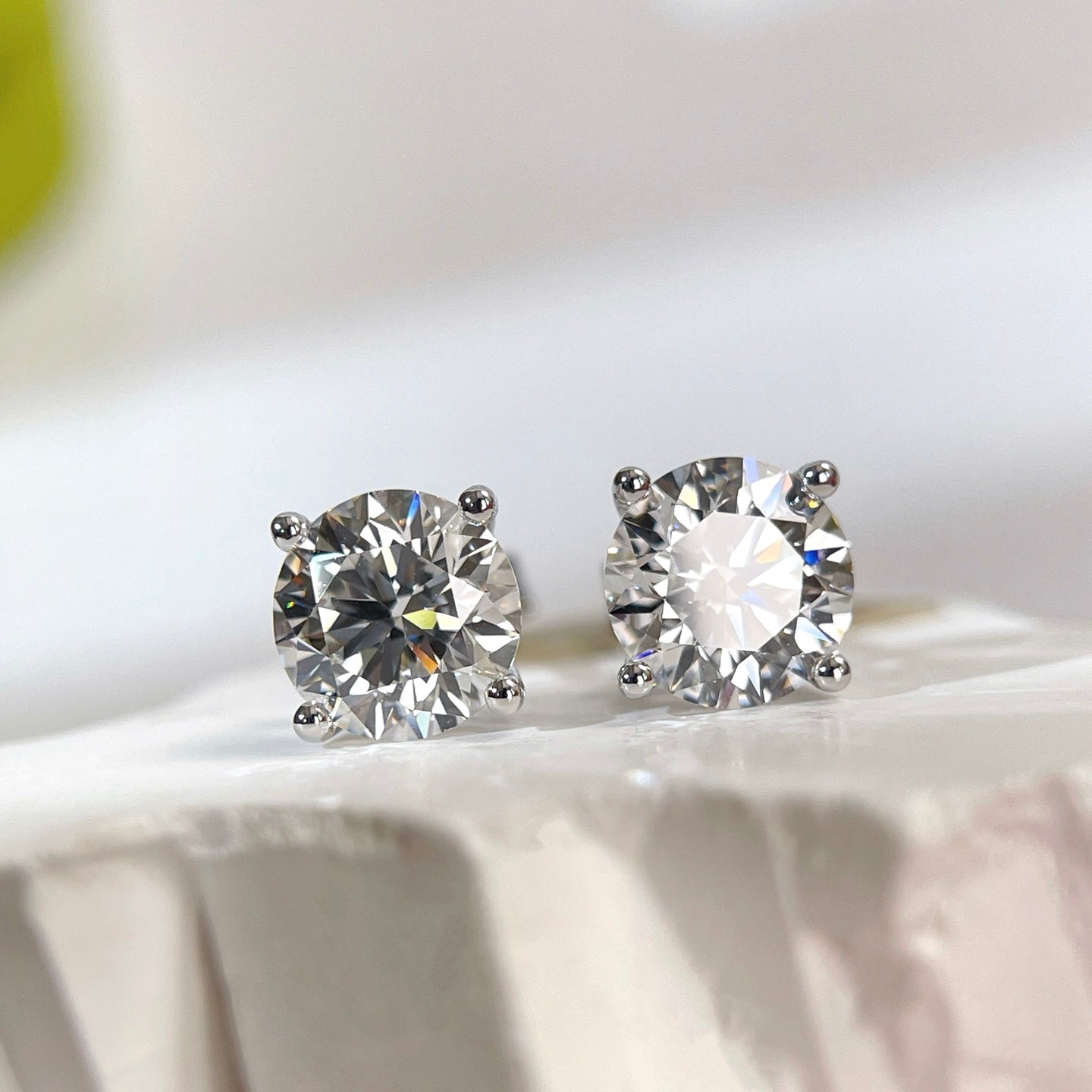 Bright front view of round lab grown diamonds in classic four-prong settings