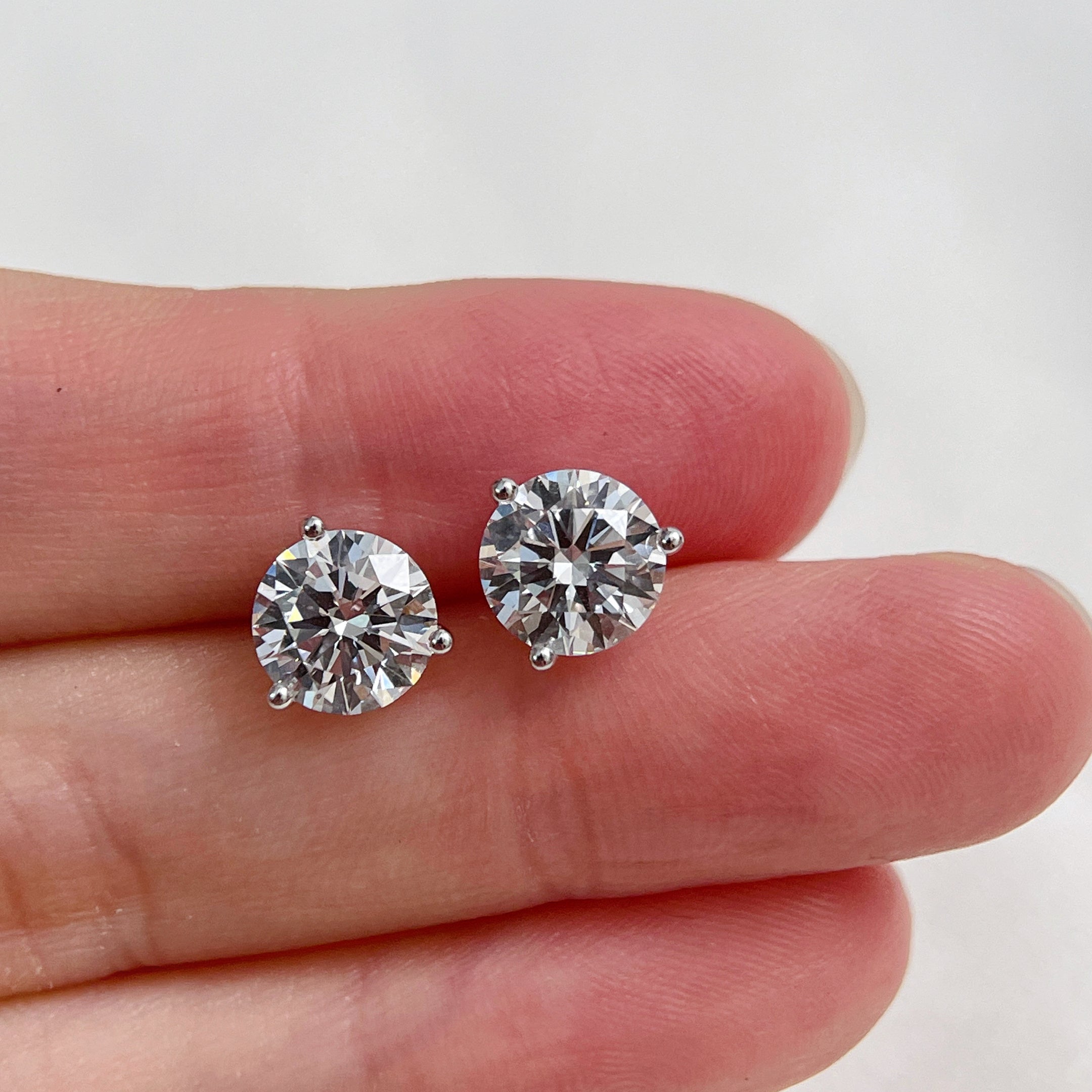 Hand-held view showing the scale of 3 CTW round lab grown diamond Martini stud earrings