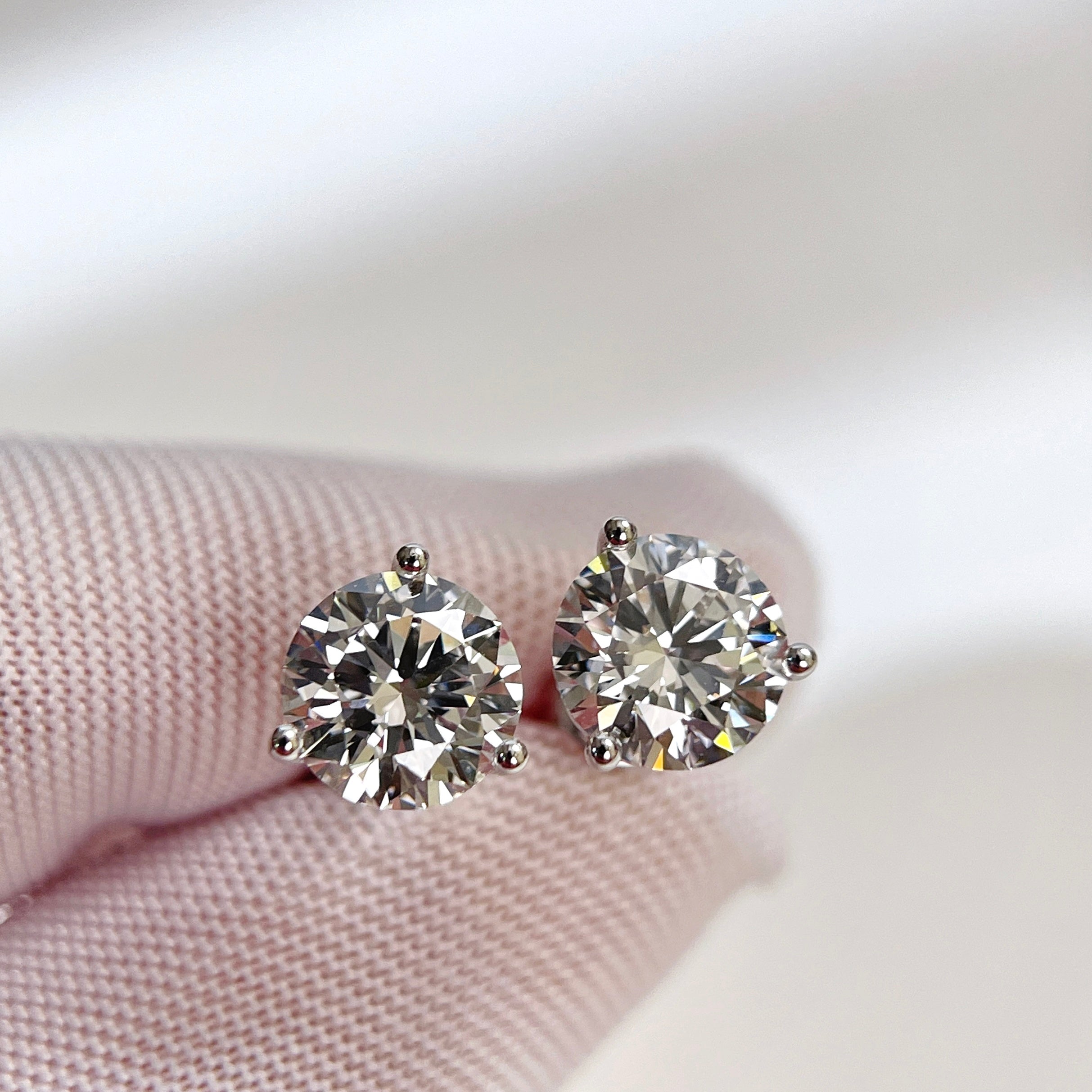 Gloved-hand close-up of D VVS2 round lab grown diamond Martini stud earrings