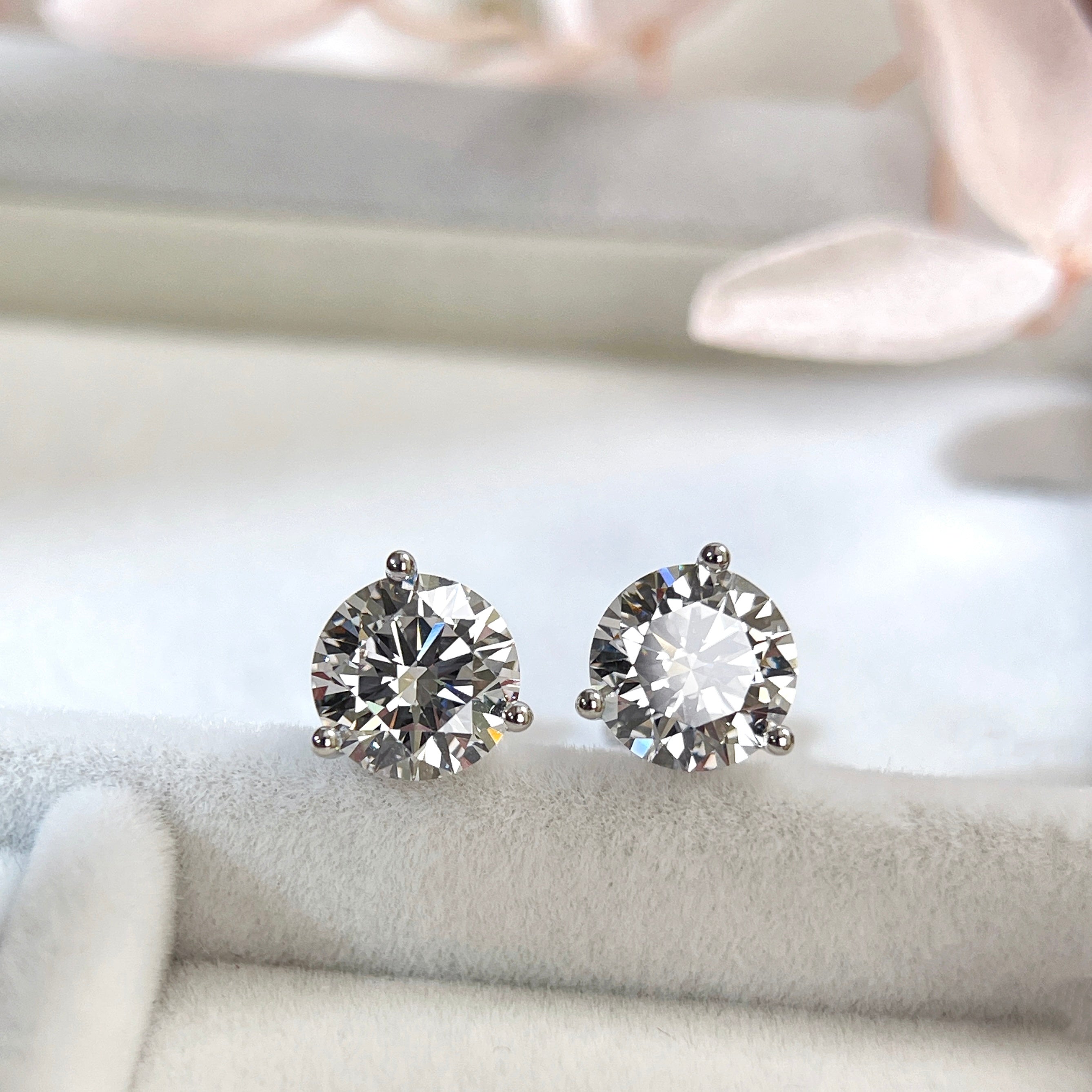 Angled display view of 3 CTW round lab grown diamond three-prong stud earrings